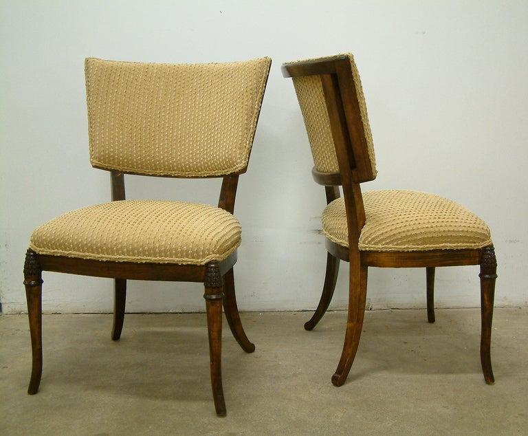 An elegant pair of dark-stained beechwood kilsmos chairs recovered in a cotton Thibaut fabric with nicely detailed double piping and finely carved leg accents.  The chairs are featured in  Thibaut advertisements. 
